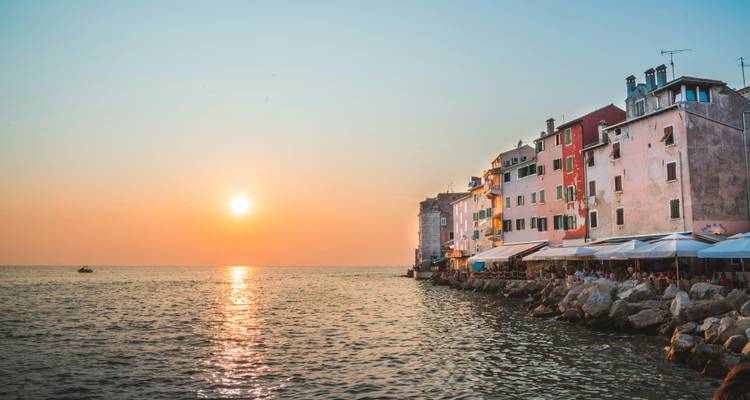 Coucher de soleil sur l'Adriatique avec une lumière pastel se reflétant sur les maisons du front de mer de Rovinj et la mer.