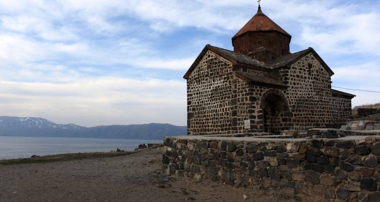 Église en pierre de Sevanavank avec ciel couvert et Lac Sevan en arrière-plan