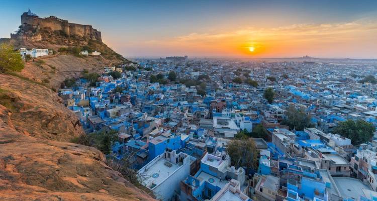 Sunset view over the blue houses of Jodhpur with Mehrangarh Fort perched on a rocky hill.