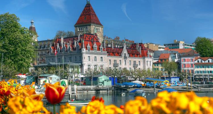 Des tulipes colorées encadrent le Château d'Ouchy au bord du lac et les bateaux par une belle journée de printemps