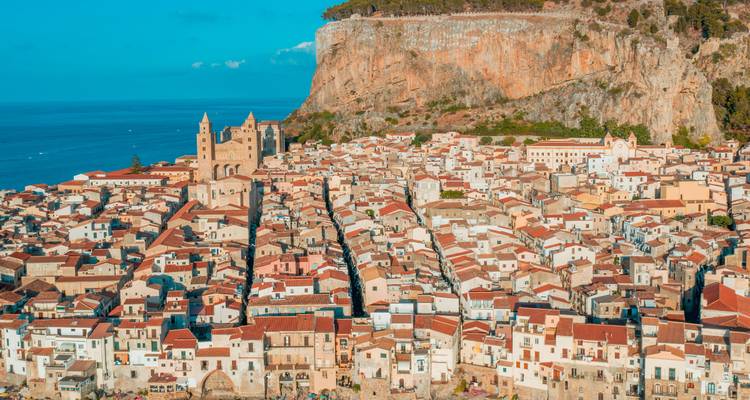 Panoramic aerial of Cefalù’s old town with twin-towered cathedral backed by rugged cliff