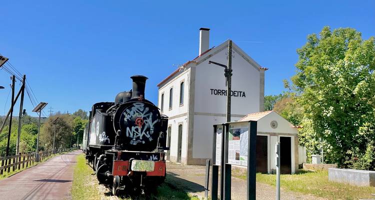 Vintage-Dampflokomotive, die neben einem weißen Bahnhof auf dem Land namens Torredeita unter klarem Himmel geparkt ist