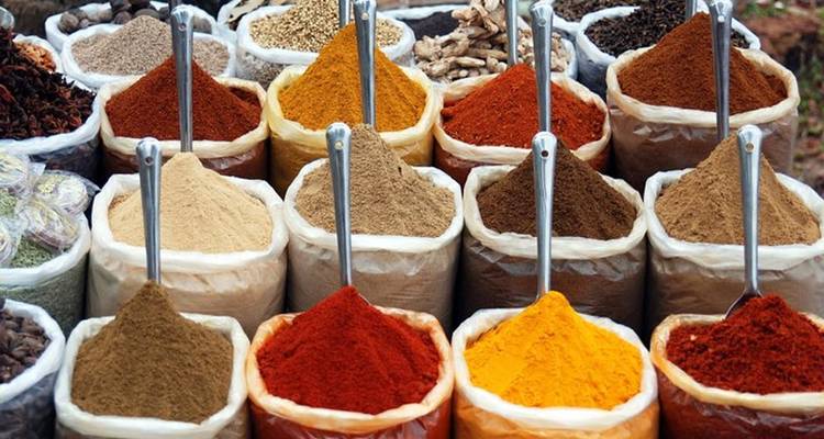 Neatly arranged sacks of colorful ground spices displayed in a market.