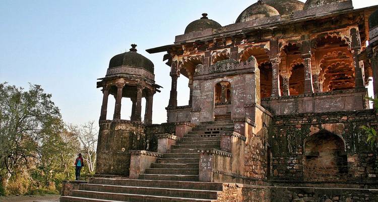 Old stone cenotaph with stairway and domed pavilions set amid trees on a hill.