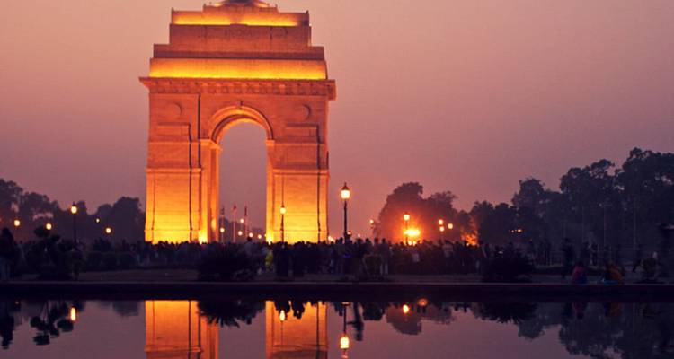 El monumento de la Puerta de la India iluminado al atardecer con un reflejo como espejo en el estanque.