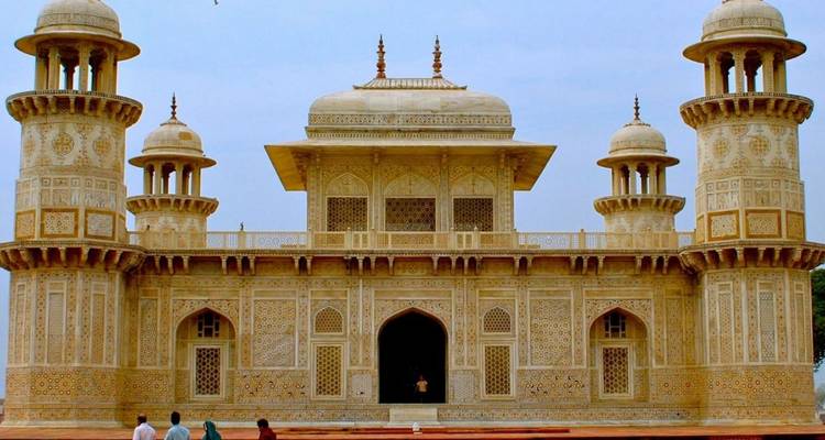 La fachada ricamente incrustada del mausoleo de Itimad-ud-Daulah con algunos visitantes caminando en primer plano.