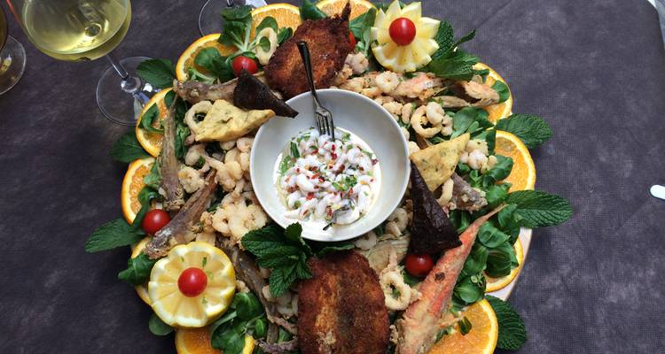 Un plateau coloré de fruits de mer siciliens, d'agrumes et d'herbes arrangés artistiquement autour d'une trempette crémeuse.