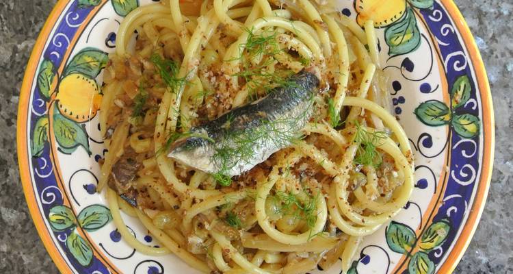 Des pâtes siciliennes traditionnelles con le sarde garnies de fenouil sont servies dans un plat en céramique peinte à la main.