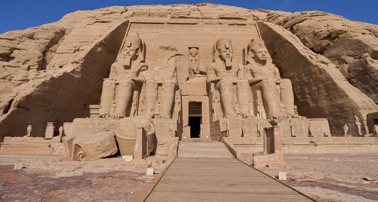 Grandes estatuas talladas en roca bordean la entrada del Templo de Abu Simbel contra un cielo azul profundo.