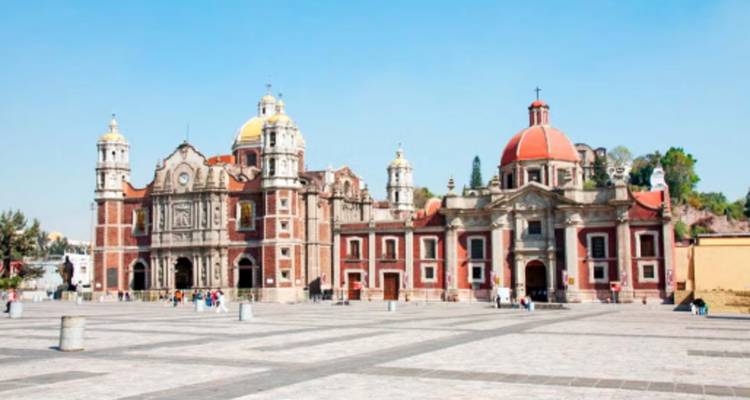 Historische basiliekgebouwen die een breed stenen plein omlijsten onder een heldere blauwe hemel in Mexico-Stad.