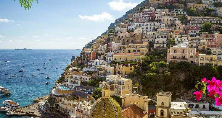 Vista clásica de la cúpula de Positano y las casas en la ladera sobre el azul Mar Tirreno con barcos dispersos.