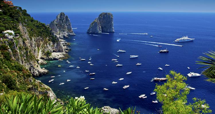 Aguas azul profundo alrededor de los farallones marinos de Capri salpicadas de yates y embarcaciones.