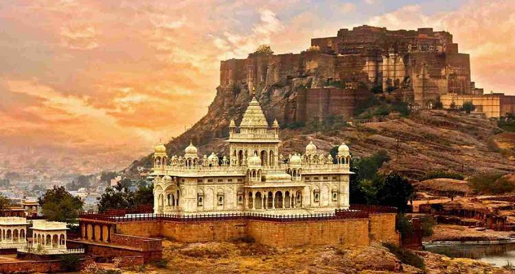 Sonnenuntergangsblick auf das weiße Marmor-Denkmal Jaswant Thada mit der dahinter aufragenden Mehrangarh-Festung in Jodhpur.