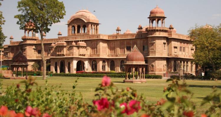 Eleganter Sandstein-Lalgarh-Palast eingerahmt von blühenden Blumen in Bikaners gepflegten Gärten.