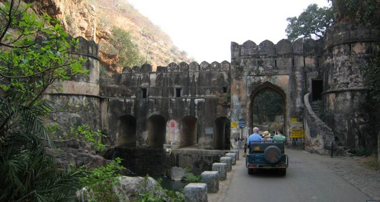 Un jeep abierto con turistas atraviesa una antigua puerta de piedra en el Fuerte de Ranthambore.