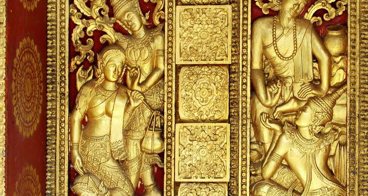 Close-up of intricate golden bas-relief figures and floral motifs adorning a red temple door panel.