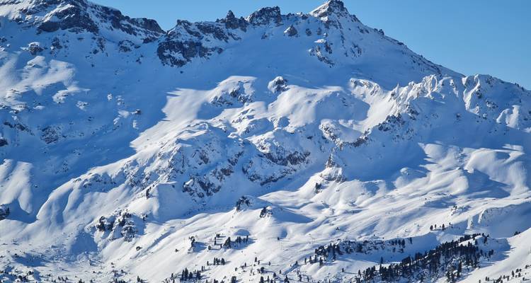 Vista nítida de cumbres alpinas dentadas cubiertas de nieve bajo un cielo invernal azul despejado.