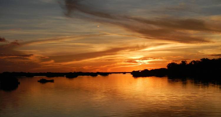Golden sunset paints the Amazon River and silhouetted islets.