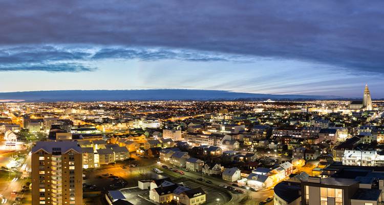 Twilight panorama of Reykjavik with city lights twinkling beneath a dramatic cloud band.