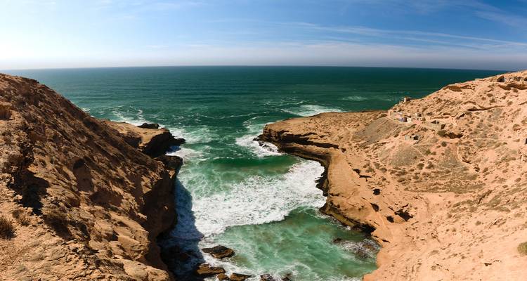 Garganta costera atlántica dramática con olas turquesas estrellándose entre acantilados desérticos rocosos y empinados.