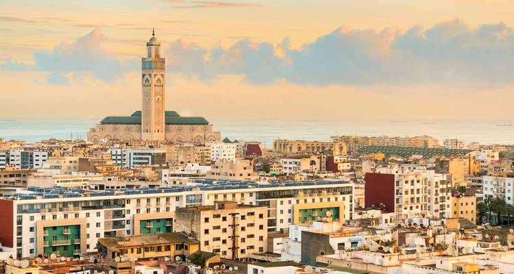 Paisaje urbano de Casablanca al amanecer dominado por la alta Mezquita Hassan II junto al Océano Atlántico.