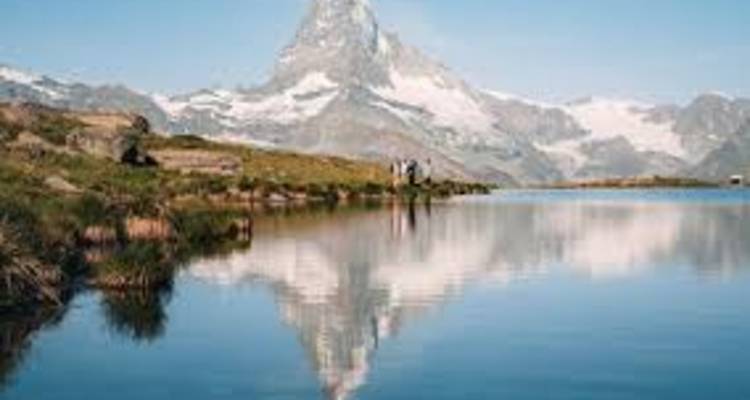 Crystal lake mirroring the iconic Matterhorn peak under a clear blue sky.