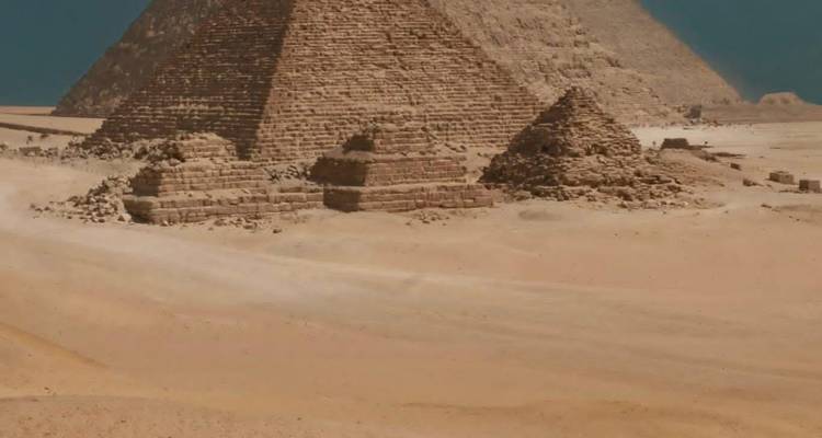 Eine Reihe kleinerer Pyramiden und sandige Wüstenweite unter blauem Himmel