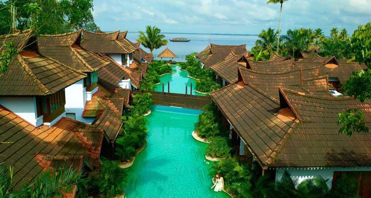 Luxuriöses Resort im Lagunen-Stil mit gefliesten Kerala-Villen säumt einen türkisfarbenen Kanal mit Blick auf einen weitläufigen See.