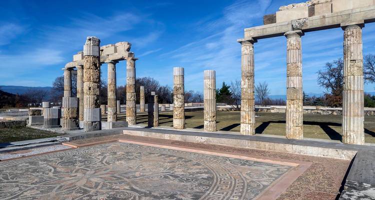 Colonnes debout et sol en mosaïque d'une basilique antique sous un ciel bleu clair.
