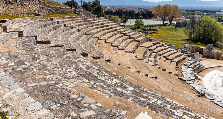 Les gradins de pierre d'un théâtre antique s'incurvent gracieusement à travers une colline surplombant une vallée moderne.