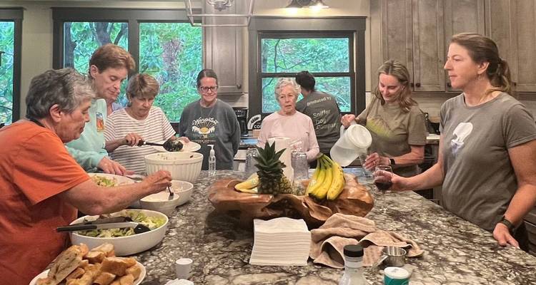 Des voyageurs se rassemblent autour d'un îlot de cuisine pour préparer de la nourriture et des boissons dans l'intérieur douillet d'un chalet.