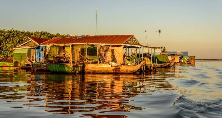 Rangée de maisons flottantes colorées se reflétant sur les eaux calmes du Tonlé Sap à l'heure dorée