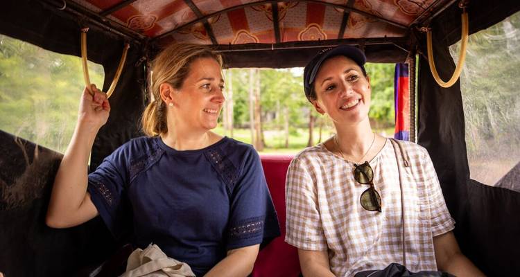 Deux amis souriants en roulant dans un tuk-tuk ouvert à travers la campagne verdoyante