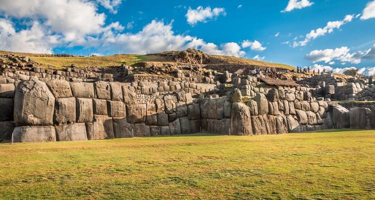 Panoramic view of the stepped stone terraces of Saqsaywaman under a vibrant blue sky.