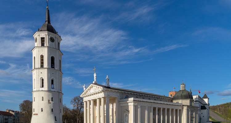 The white bell-tower and classical façade of Vilnius Cathedral under a crisp blue sky.