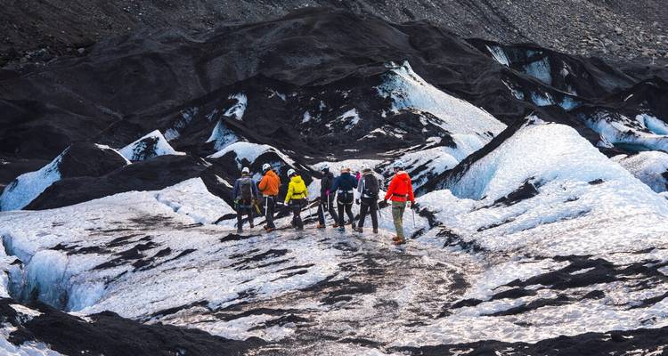 Un groupe d'aventuriers portant des casques et des crampons traverse une glace glaciaire frappante en noir et blanc.