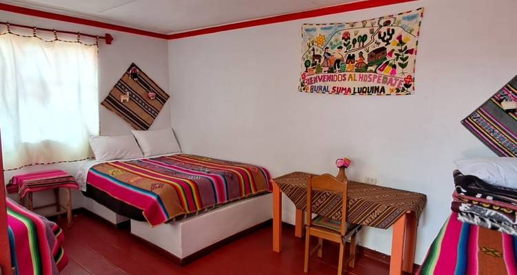 Chambre d'hôte simple décorée avec des couvertures traditionnelles aux couleurs vives et des tapisseries murales typiques des gîtes du lac Titicaca.