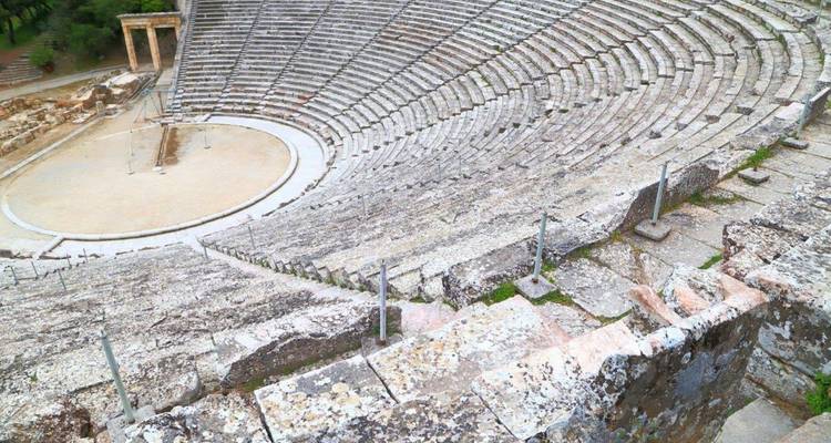 Des gradins en pierre s'incurvent autour de l'ancien théâtre d'Épidaure sur un fond montagneux.