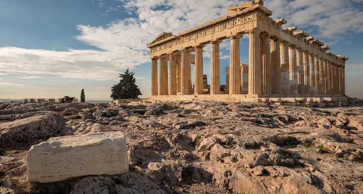 Iconic Parthenon temple atop the Acropolis surrounded by rocky terrain and dramatic sky.