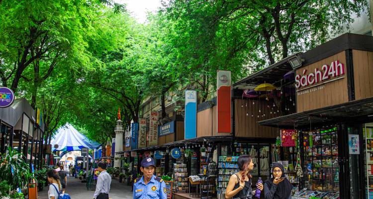 Baumgesäumte Fußgänger-Buchstraße mit Ständen, Lesern und bunten Schildern in Ho-Chi-Minh-Stadt.
