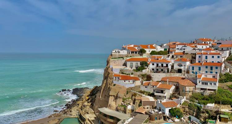 Weißgetünchtes Dorf mit Terrakottadächern, das auf einer Klippe über türkisfarbenem Atlantikwasser thront.