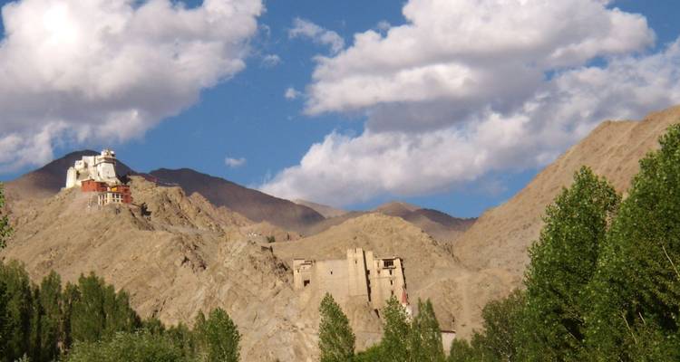 Hilltop monasteries and ruined structures set against arid mountains and scattered trees
