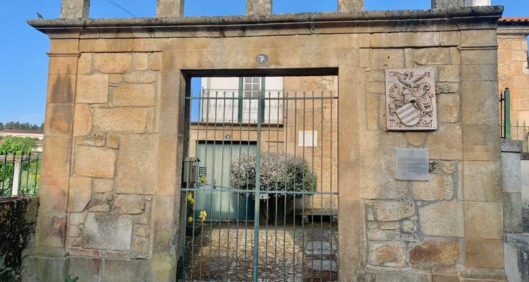 Puerta de entrada de piedra con barras de metal y escudo de armas tallado en una casa de pueblo histórico