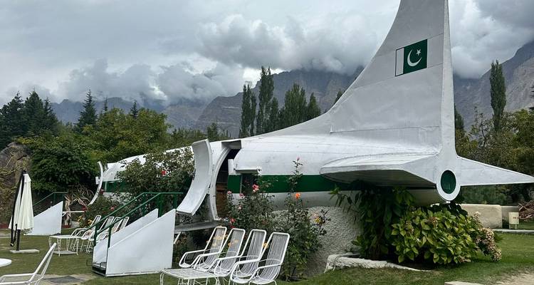 Cola de avión desmantelado reutilizada como instalación extravagante de jardín con montañas al fondo.
