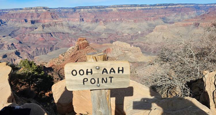 Letrero de madera que dice 'OOH AAH POINT' encaramado en el borde con vistas al vasto Gran Cañón.