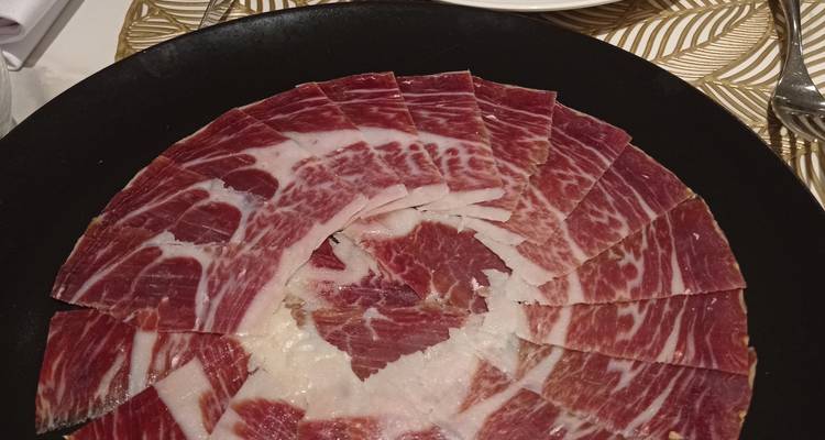 Assiette de jamón ibérico finement tranché, élégamment présenté sur une assiette noire