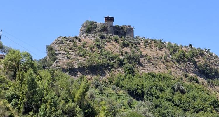 Stone fortress tower perched on a rugged hill surrounded by green vegetation