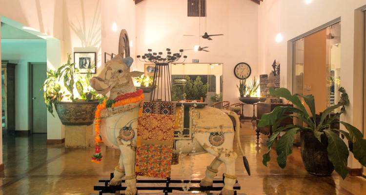 Hall d'hôtel éclectique présentant une statue de taureau en bois décorée et un éclairage ambiant chaleureux.