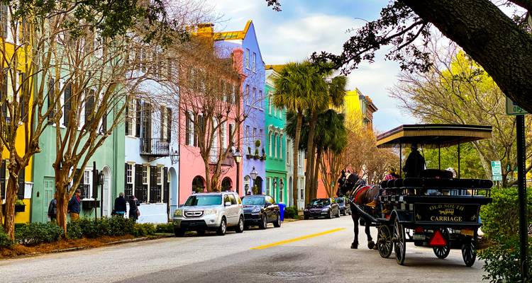 Colorful historic Rainbow Row houses with horse-drawn carriage on a sunny Charleston street.