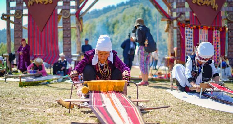 Kirgisische Frauen, die auf traditionellen Webstühlen bei einem Outdoor-Kulturfestival weben